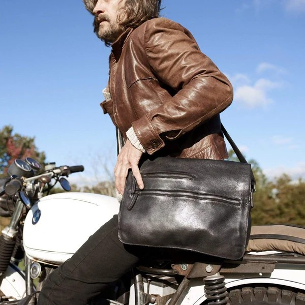 Man posing on a motorbike while wearing a leather bag